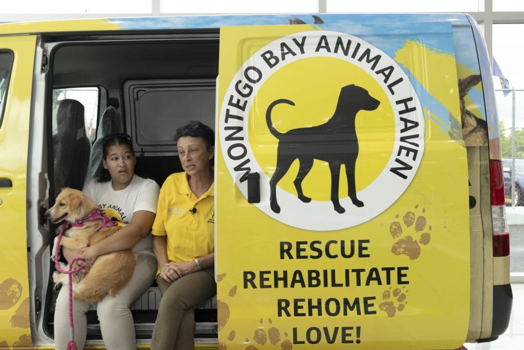 Team from Rwanda Animal Welfare Organisation stand with information board.